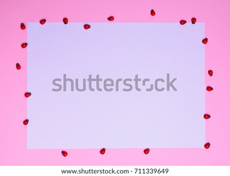 blank white sheet of paper on a pink background, around the red ladybugs