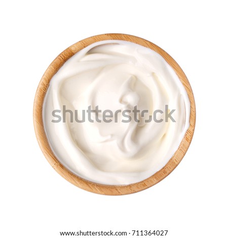 Sour cream in a wooden bowl isolated on white. Dairy product. Top view. Royalty-Free Stock Photo #711364027