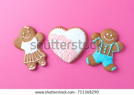 Homemade gingerbread man. Couple and heart on pink background. Concept of love, valentine day. Picture for a menu or a confectionery catalog. Invitation or greeting card.