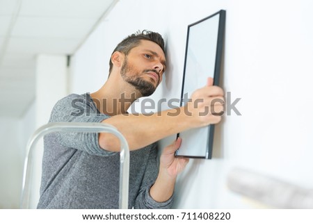 repairman putting picture frame onto wall