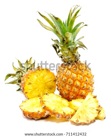 Fresh sliced pineapple and one whole with green leaves isolated on white background