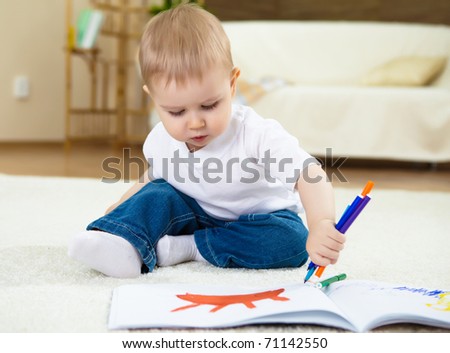 little boy drawing with color pencil and sitting on the floor at home