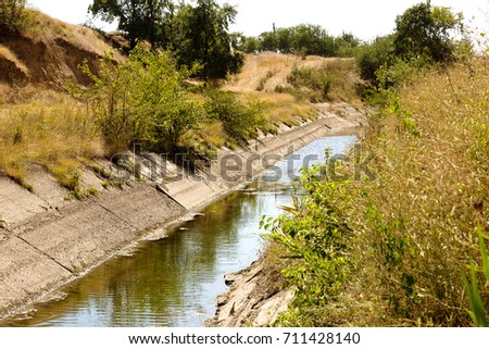 An old drying up irrigation channel with remains of water at bottom of canal. Blockade of water irrigation artery of Crimea. Artificial drought, destruction, collapse in irrigated agriculture