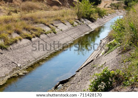 An old drying up irrigation channel with remains of water at bottom of canal. Blockade of water irrigation artery of Crimea. Artificial drought, destruction, collapse in irrigated agriculture
