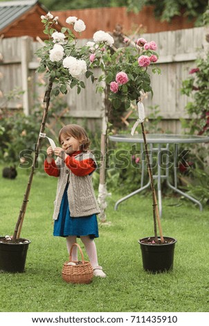 Little girl with a pink and white roses in a pots