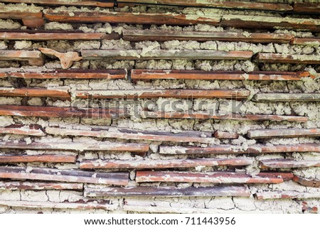 Wall constructed of thin orange roof tiles.