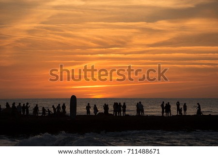 Golden sunset on the sky with beautiful clouds and tourist on the beach.