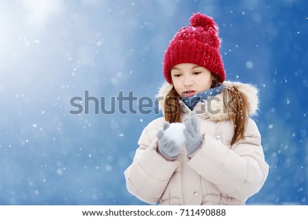 Adorable little girl having fun in beautiful winter park. Cute child playing in a snow. Winter activities for kids.