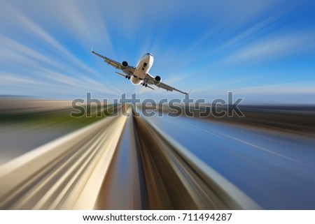 Airplane in motion over roadway on blur blue sky background