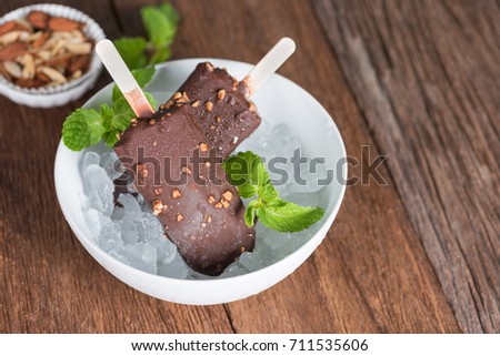 Ice cream covered with chocolate and almonds sticks in ice.