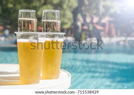 Champagne and beer on the background of the pool