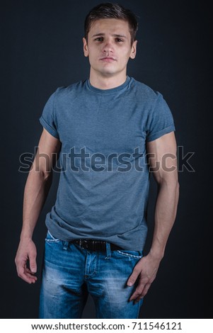 young guy with athletic body posing in Studio. smiling and showing muscles. Wallpapers for your desktop. clothing style: street. emotional portrait