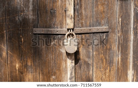 old rusty padlock closed on the wooden barn door. photo close up