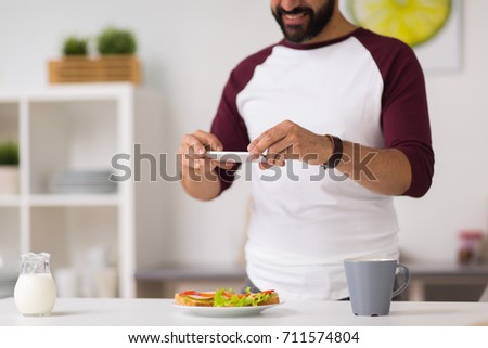 food, healthy eating and people concept - man with smartphone having breakfast and photographing sandwiches at home kitchen
