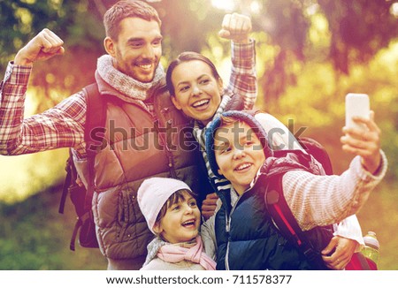 travel, tourism, hike and technology concept - happy family with backpacks taking selfie by smartphone outdoors