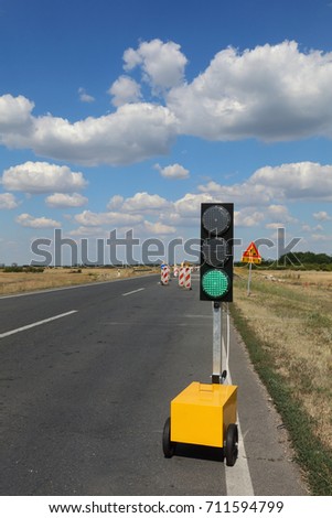 Roadworks, traffic light and road signs at a highway on reconstruction with blue sky and clouds