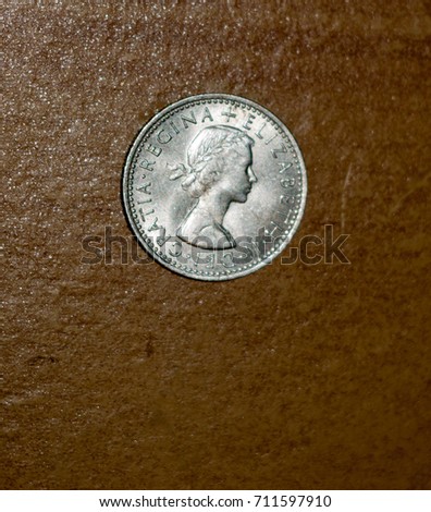 An old six pence penny silver coin with a background table top wood; England; UK