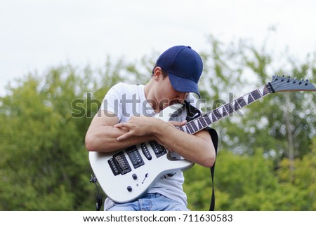 Smiling guy kiss a gray guitar