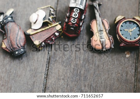 hobby and leisure object concept image, miniature violin, clocks,travel bag and train on wooden floor.selective focus shot