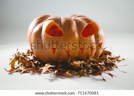Jack o lantern on autumn leaves over white background