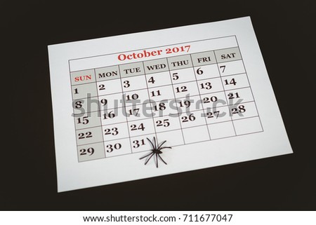 High angle view of artificial spider on calender over black background