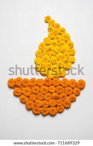 Diya shape rangoli made using marigold flowers on Diwali  OR Pongal OR Onam Festival over white background, selective focus
