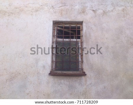 An old window with bars on a white wall