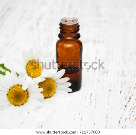 Massage oil and chamomile on a old wooden background
