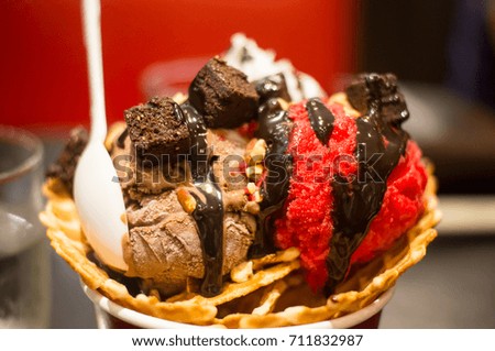 Ice cream chocolate and raspberry paste on crisp waffles in cups on the table