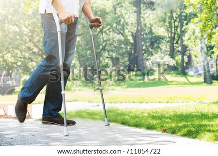 Close-up Of Man Walking With Crutches In Park Royalty-Free Stock Photo #711854722