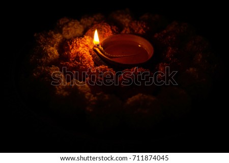flower rangoli for Diwali or pongal or onam made using marigold or zendu flowers and red rose petals over white background with diwali diya kept in the middle, selective focus
