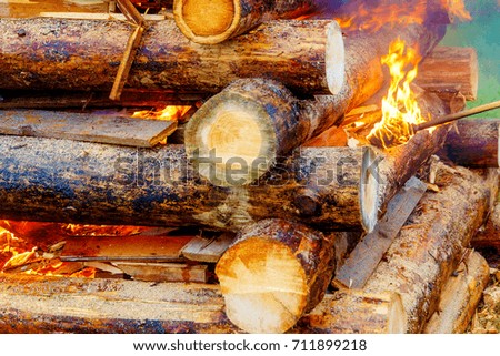 setting big bonfire made of logs on fire with torch.