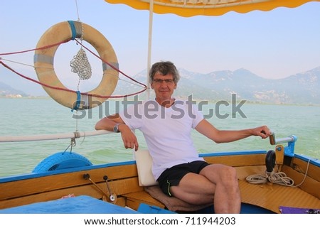On lake Skadar, Montenegro: A man handles the steering oar of an excursion boat. Lake Skadar national park, southeast europe. 