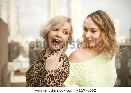two blond women friends standing on the balcony and speaking