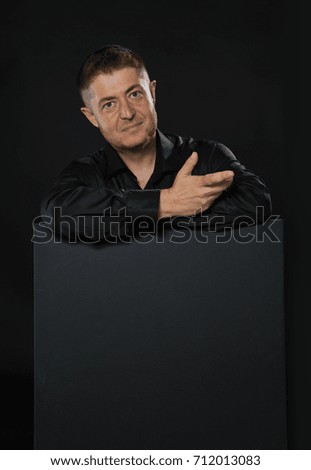 Young confident man portrait of a confident businessman showing presentation, pointing placard black background. Ideal for banners, registration forms, presentation, landings, presenting concept.