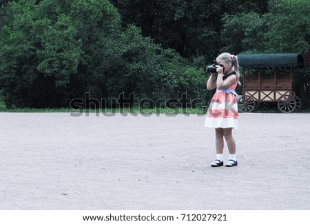 Little girl by the paparazzi. Child taking pictures in nature.
