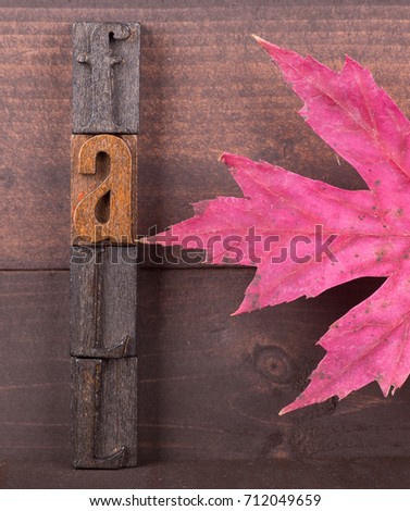 Wood letters spelling Fall with autumn maple leaf on a wooden background