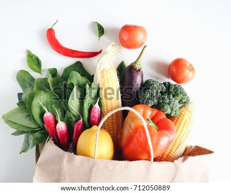 Fresh and juicy raw vegetables in a paper shopping back. White background. Broccoli, spinach, corn, tomatoes, chilling pepper,. Top view, side view. Vegetarian food