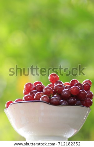 The purple grape in glass dish and white bokeh on green background 