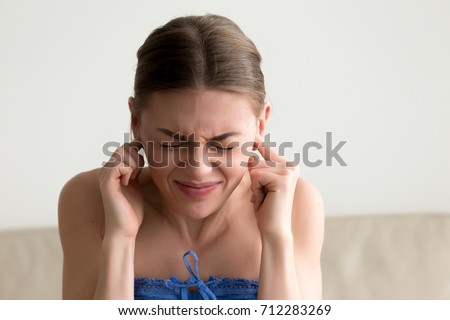 Young annoyed woman sticking fingers in ears with eyes closed, not listening to loud noise, ignoring stressful environment, stubborn teen refuses hearing, feels ear ache, tinnitus, head shot portrait Royalty-Free Stock Photo #712283269