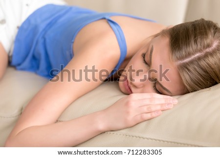 Young sleep deprived woman lying asleep on sofa, attractive girl taking nap at home, resting on comfortable couch, exhausted teenager dozing after sleepless night, feeling lack of sleep, stress relief Royalty-Free Stock Photo #712283305