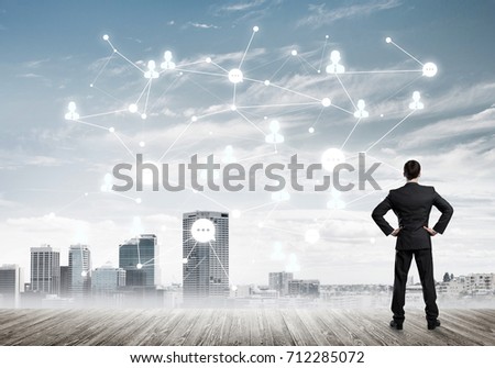 Back view of businessman looking at modern cityscape and connection concept