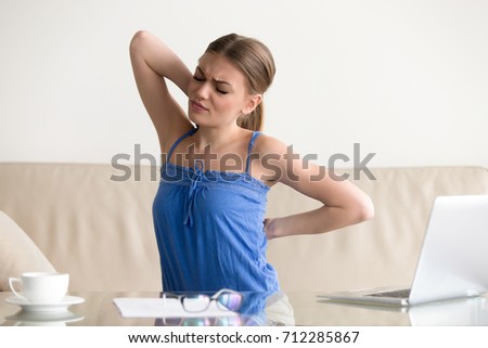 Young woman stretching suffering from sudden back pain, tensed muscles after long sedentary work in incorrect posture at home, stressed girl having backache, feeling ache between shoulder blades Royalty-Free Stock Photo #712285867