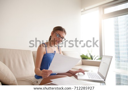 Young woman wearing glasses holding business document using laptop, hr manager working at home composing e-mail job offer to new open vacancy candidate, typing answer letter after resume consideration