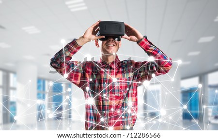 Young man with virtual reality headset or 3d glasses over connection background. Mixed media