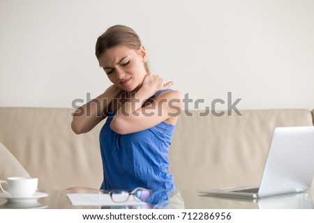 Tired woman feeling neck pain, massaging tense muscles, suffering from chronic shoulder back ache after long work on laptop computer at home, sedentary work, incorrect posture problems, fibromyalgia Royalty-Free Stock Photo #712286956