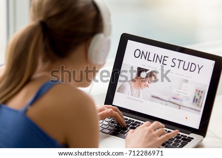 Online study concept, woman in headphones searching free audio course for individual self-tuition, student using laptop for e-learning, distance learning, rear view over shoulder, focus on screen Royalty-Free Stock Photo #712286971