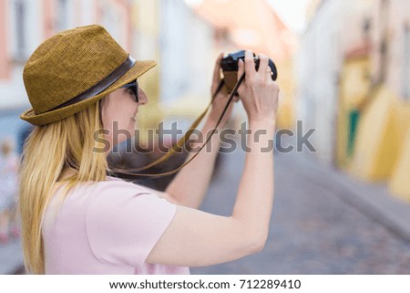 travel and photography concept - young woman tourist walking in city with camera
