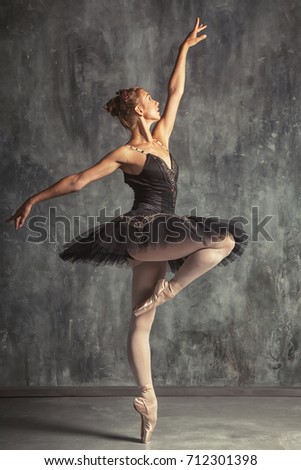 Young beautiful woman prima theater in a black festive pack, white pantyhose, white pointe shoes beautifully dancing russian ballet in a black dance studio