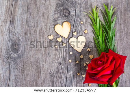Heart shape with green foliage and red rose flower on wood texture background, Studio shot on wooden background.